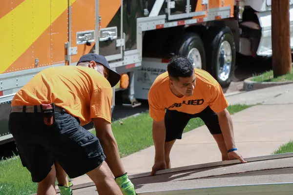 Two Bailey's movers in Allied shirts working beside the truck
