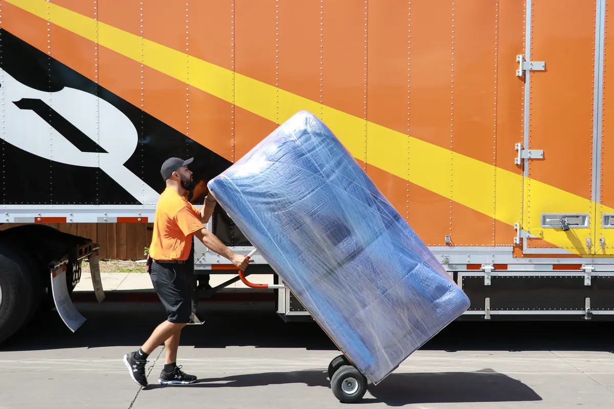 Bailey's mover wheeling a wrapped piece of furniture to an Allied trailer